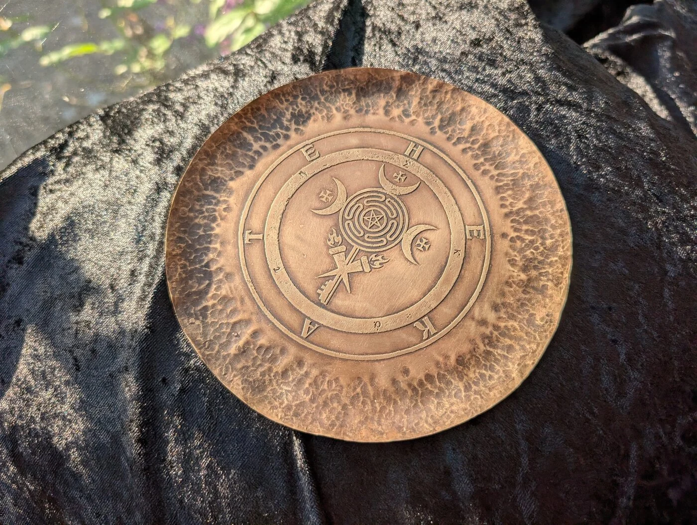 Hammered copper Hekate altar plate with etched ritual symbols in sunlight by BorboroForge
